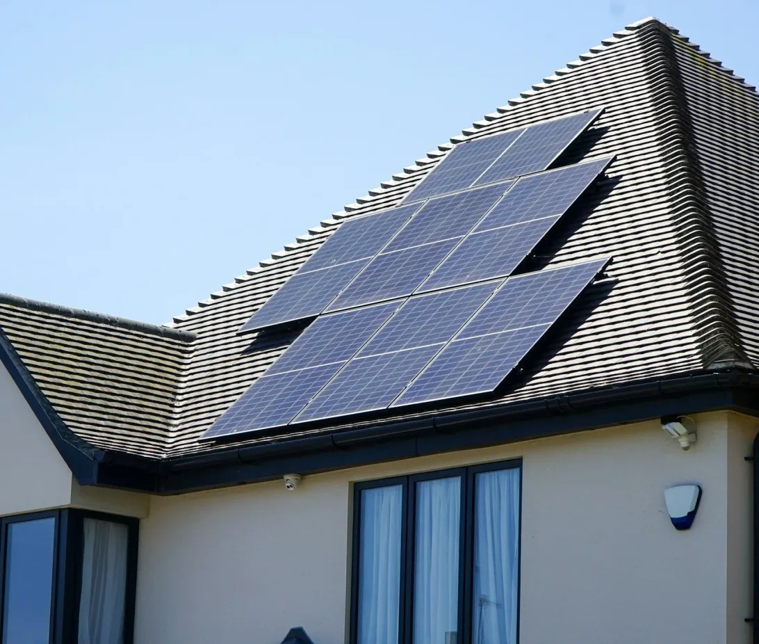 Solar panels on the pitched roof of a house against a blue sky